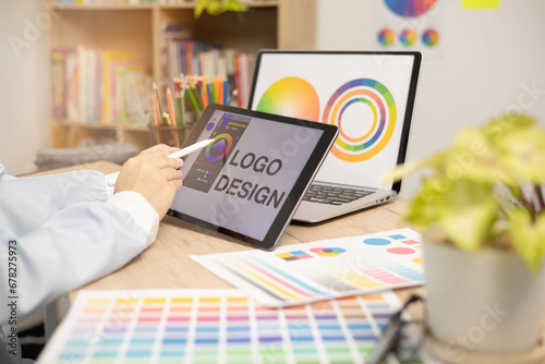 Designer creating graphic logo on a table using tablet and laptop photo