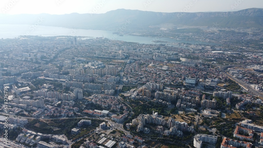 Aerial shot of a cityscape and a lake near the high mountains during the daytime
