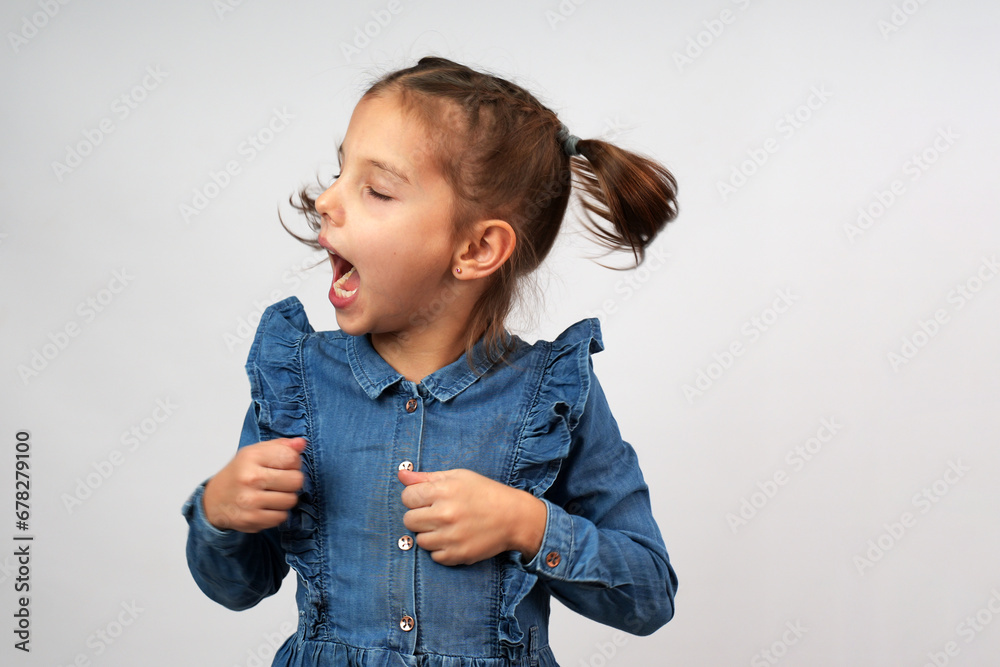 Close-up portrait of screaming little girl in denim dress Close-up portrait of screaming little girl in denim dress