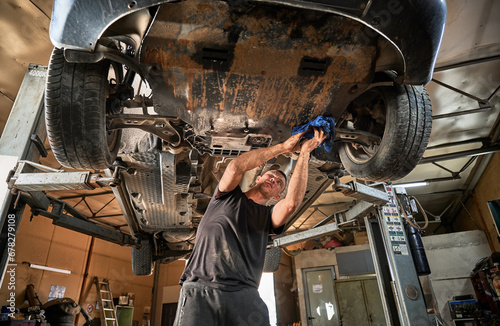 Canvas Print Repairman, worker repairing car, holding rag, wiping