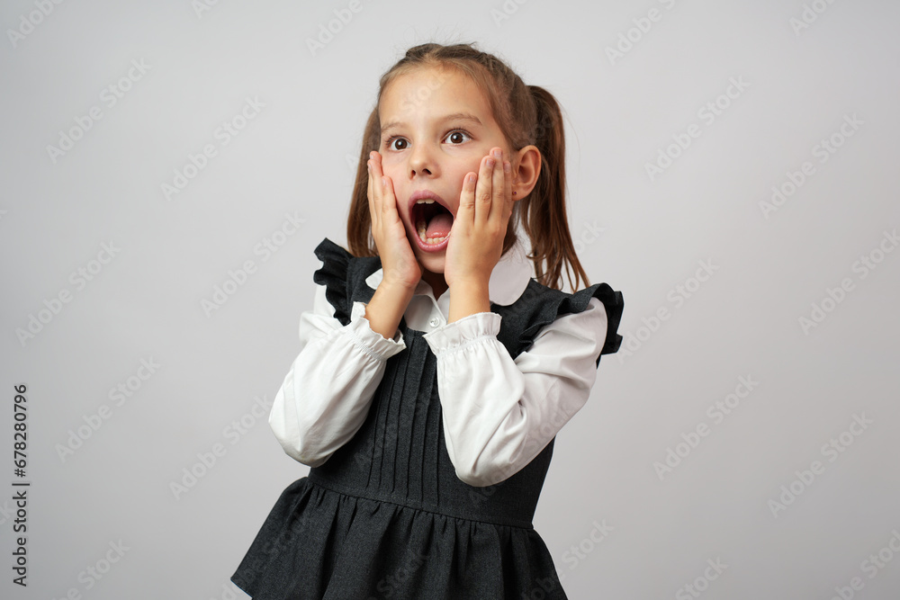 Shocked kid girl wearing school uniform against white background Shocked kid girl wearing school uniform against white background