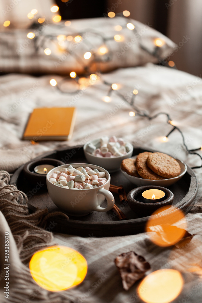 warm cozy bedroom interior with cup of hot chocolate on tray, candles christmas lights warm cozy bedroom interior with cup of hot chocolate on tray, candles christmas lights
