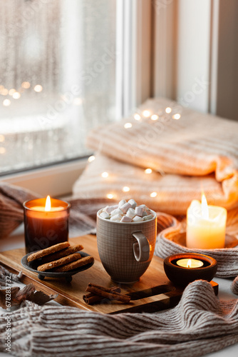 warm cozy window arrangement, winter or autumn concept, coffe, candles throw lights