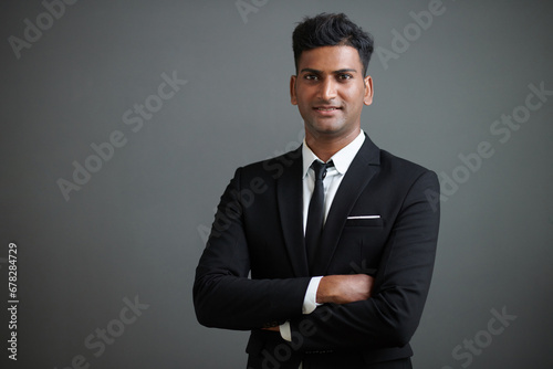 Studio portrait of smiling confident young businessman in suit crossing arms and looking at camera photo