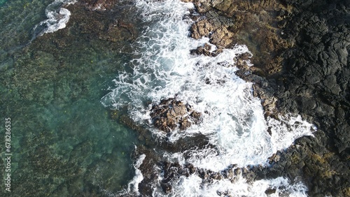 High-angle shot of sea waves crashing on a rocky shore of a beach