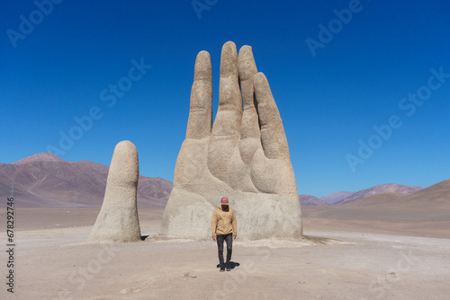 Young man in front of the Hand of the desert in the Atacama desert, Chile