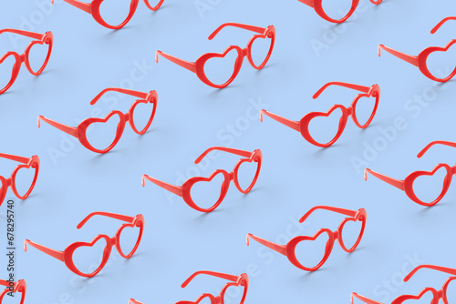 Pattern made with red heart shaped sunglasses on pastel color background