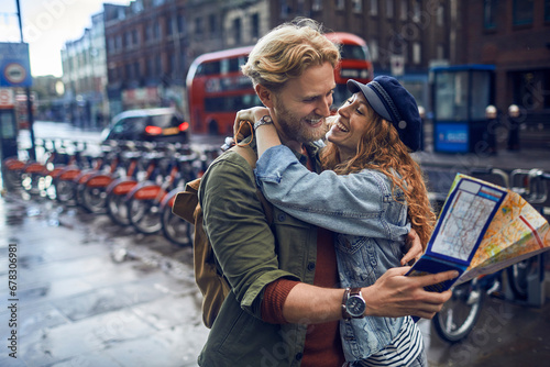 Happy young couple of travelers holding map in the city photo