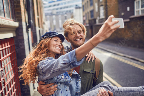 Happy young couple taking selfie together in city photo