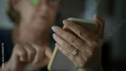 Close-up senior woman hand holding phone messaging with modern technology. Older lady texting with smartphone photo