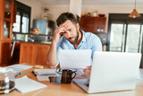 Young man holding document,paperwork,bill looking stressed at home