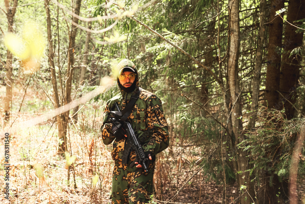 Soldier male in military camouflage uniform with weapon on war standing at summer forest background. Military man border guard in country border holding machine gun at day nature. Copy ad text space
