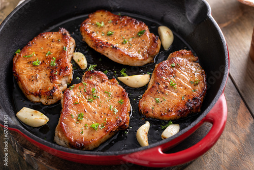 Pork chops seared in a cast iron pan with garlic