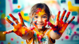 Little girl with painted hands making peace sign with paint all over her face.