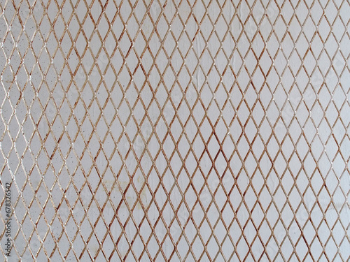 silver steel mesh in front of grey concrete wall, diagonal metallic grating for hanging products display in stall at flea market