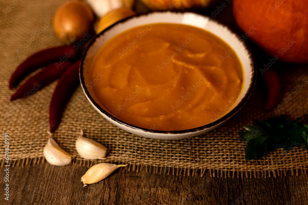 A bowl of pumpkin soup with vegetables on the table.Rustic autumn food.Diet soup A bowl of pumpkin soup with vegetables on the table.Rustic autumn food.Diet soup