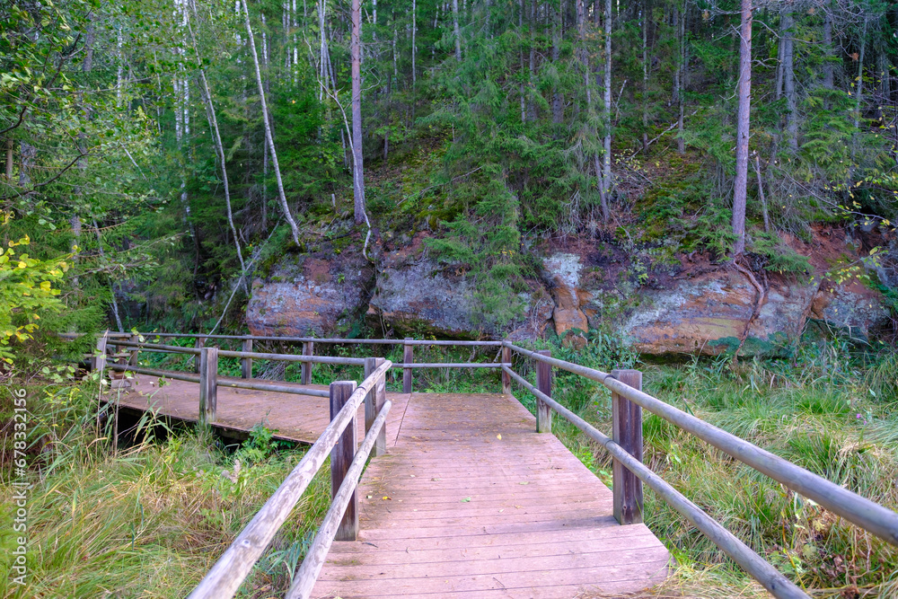 A wooden bridge, a path with a railing as a place for tourists to walk to an environmental object that is difficult to access. Red sand cliffs. Autumn in Latvia A wooden bridge, a path with a railing as a place for tourists to walk to an environmental object that is difficult to access. Red sand cliffs. Autumn in Latvia