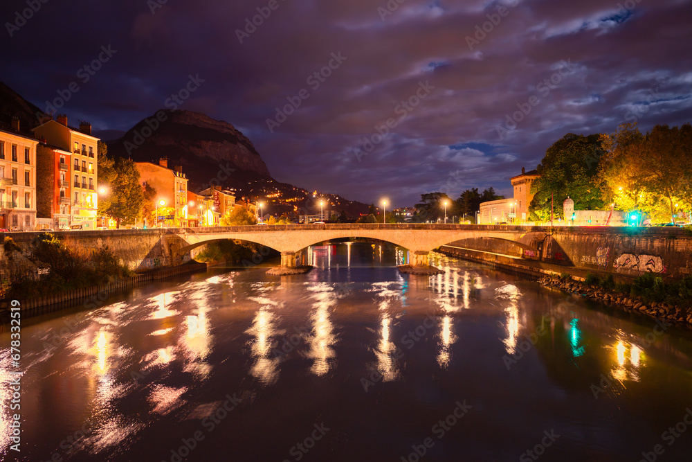 Grenoble, France - September 29, 2023: A bridge across Isere river in Grenoble, night and illuminations, light reflections in the water