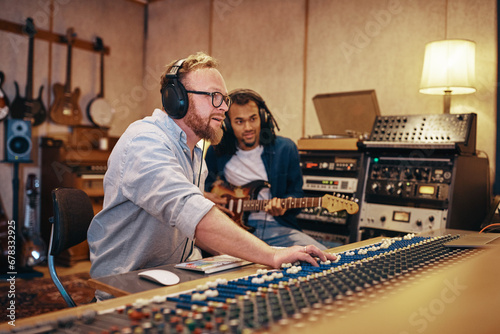 Music producer and guitarist working together in a studio photo