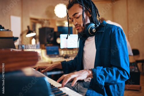 Young musician playing keyboards in a recording studio photo