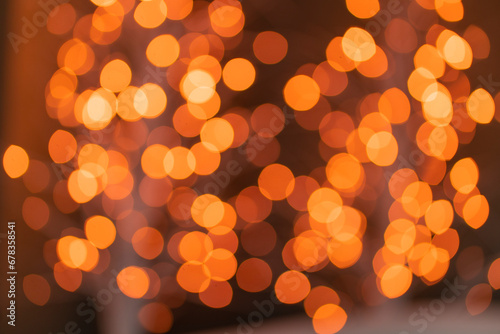 Christmas golden glowing background. Golden festive abstract shiny defocused background with flashing garlands. Tinsel blurred gold bokeh on a black background.