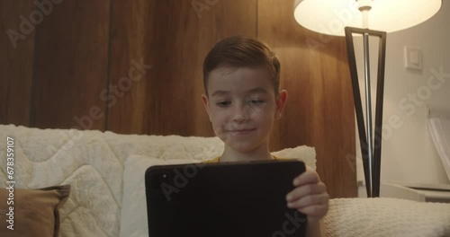 Close up boy 7-8 years afraid child using tablet in living room, Small child hold pad computer surfing not safe content online internet at home concept safety parental security child on social media. photo