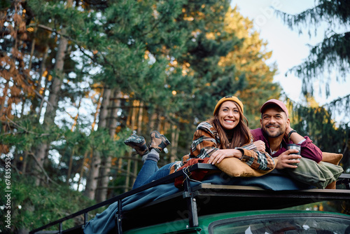 Young happy couple enjoying in view from their camper trailer's roof in nature