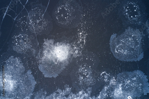 An aerial view of a frozen pond with a patterned surface of patches of crystalline ice. Shot from a drone. Copy space.