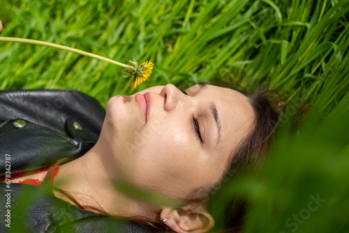 The girl lies in the grass and enjoys the aroma of dandelion