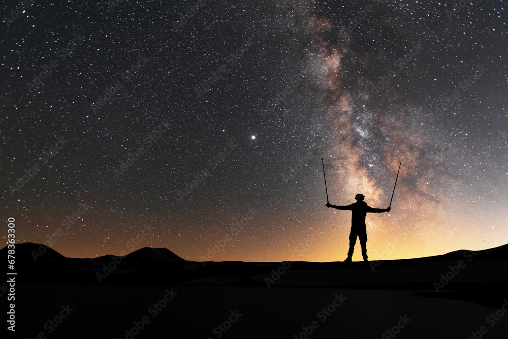 Silhouette of a hiker standing on the hill, on the milky way galaxy background. Cosmos wallpaper. 