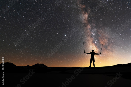 Silhouette of a hiker standing on the hill, on the milky way galaxy background. Cosmos wallpaper.  © Inga Av