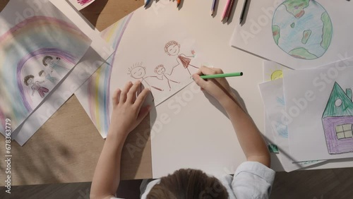 Talented boy expresses his artistic skills through drawing creating beautiful image of his family, top view. Child's perception of blissful and united family. Dream of emotional intimacy within family