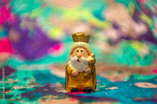 Wise Man Melchior in hand painted clay figurine with colorful and out of focus background photo