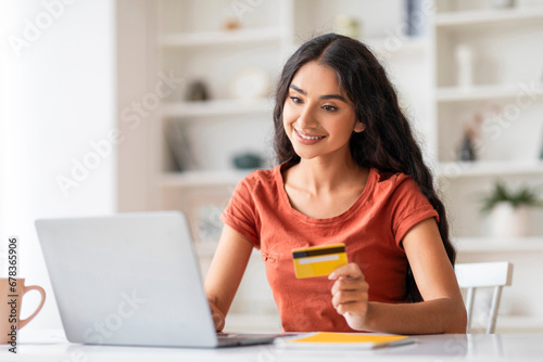 Young woman holding credit card and using laptop
