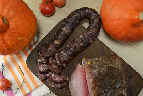 Homemade Chunks of salted bacon, pork lard , Dry salami sausage close-up on the wooden board with pumpkins on the background. Thanksgiving concept