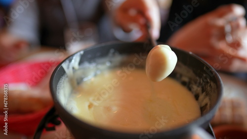 Fondue close-up of fork serving bread with cheese - Eating traditional Swiss cuisine