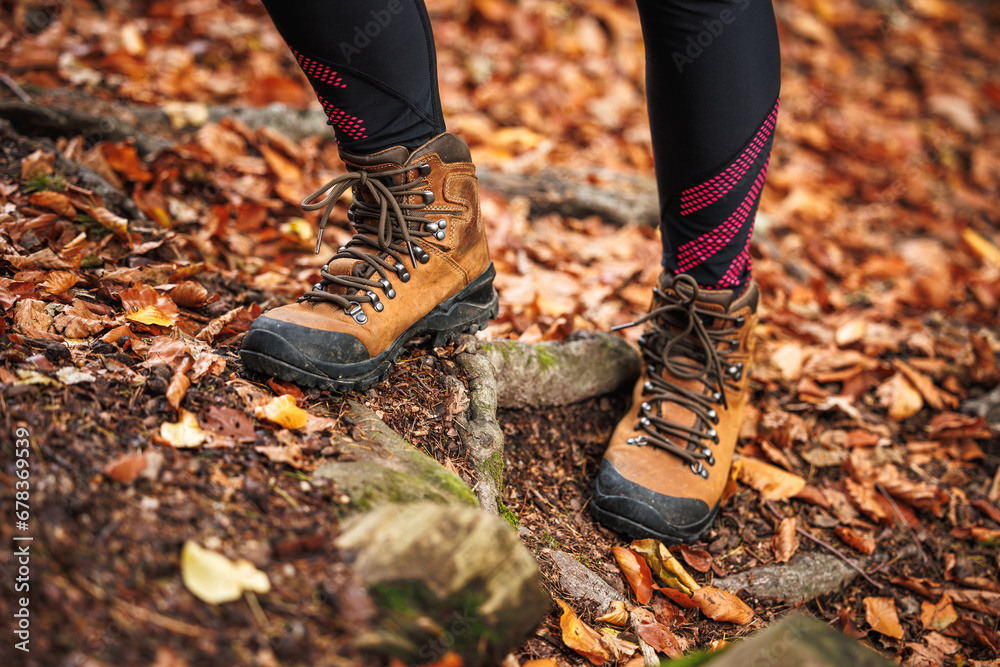 Leather hiking boot. Woman in leggings walks in the autumn forest. Sport clothing