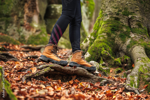 Leather hiking boot. Woman in leggings walks in the autumn woodland. Sports clothing
