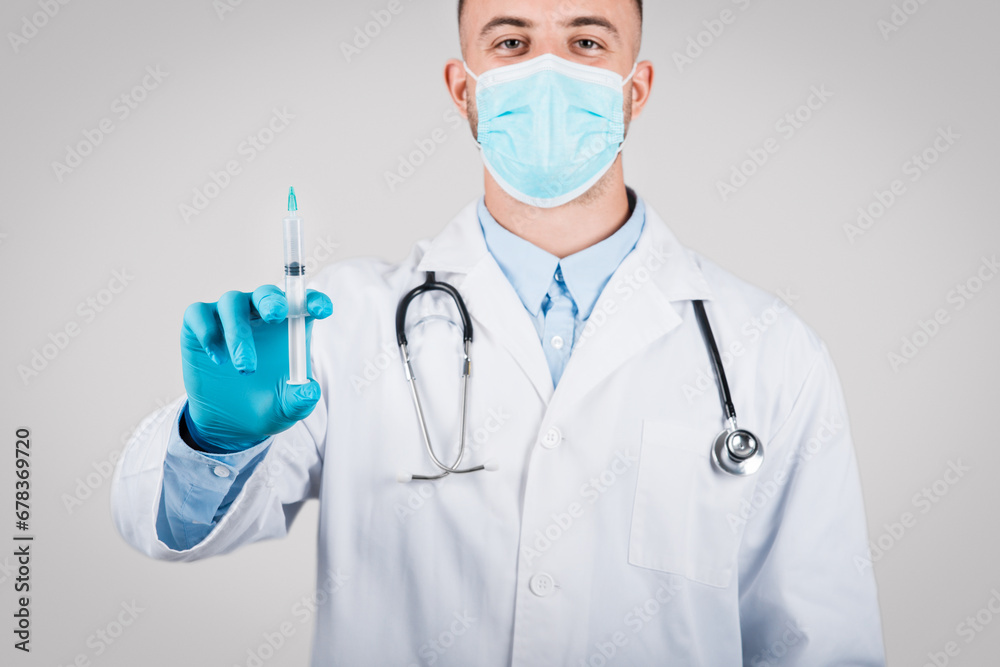 Male doctor in mask holding a syringe Male doctor in mask holding a syringe