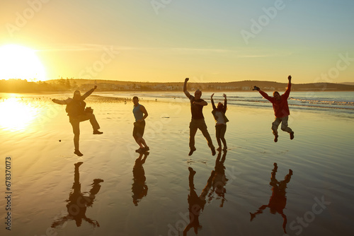 Silhouettes of people posing against the morning sky create a captivating beachscape.