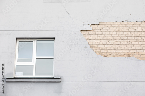 Plaster fell from the wall of the house. Gray paint and white bricks