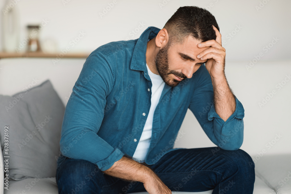 Unhappy man suffering from loneliness with head in hands indoors Unhappy man suffering from loneliness with head in hands indoors