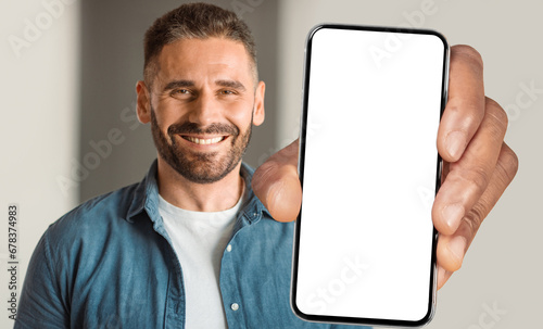 Middle aged guy displays large phone screen indoors