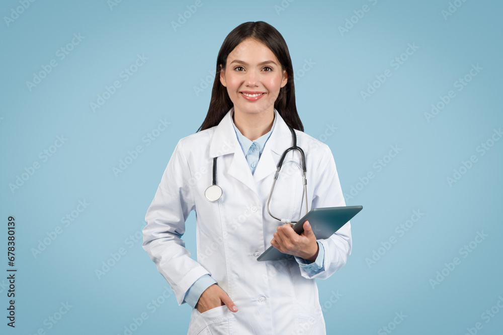 Smiling young female doctor holding tablet and smiling at camera Smiling young female doctor holding tablet and smiling at camera
