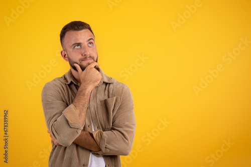 Focused pensive young caucasian man with beard in casual thinks