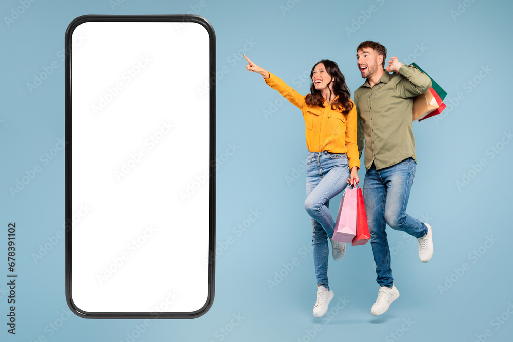 Couple with bags jumping, pointing at offer
