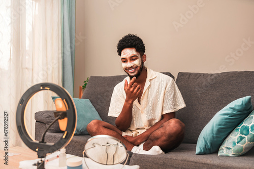 Latin man applies face mask during video blog session photo
