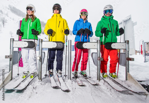 Four skiers wearing colorful jackets on a ski lift photo