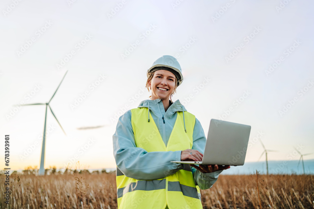 Engineer with laptop at wind farm during sunset Engineer with laptop at wind farm during sunset