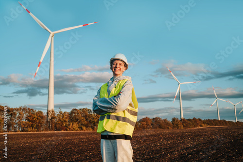 Female engineer smiling in front of wind turbines